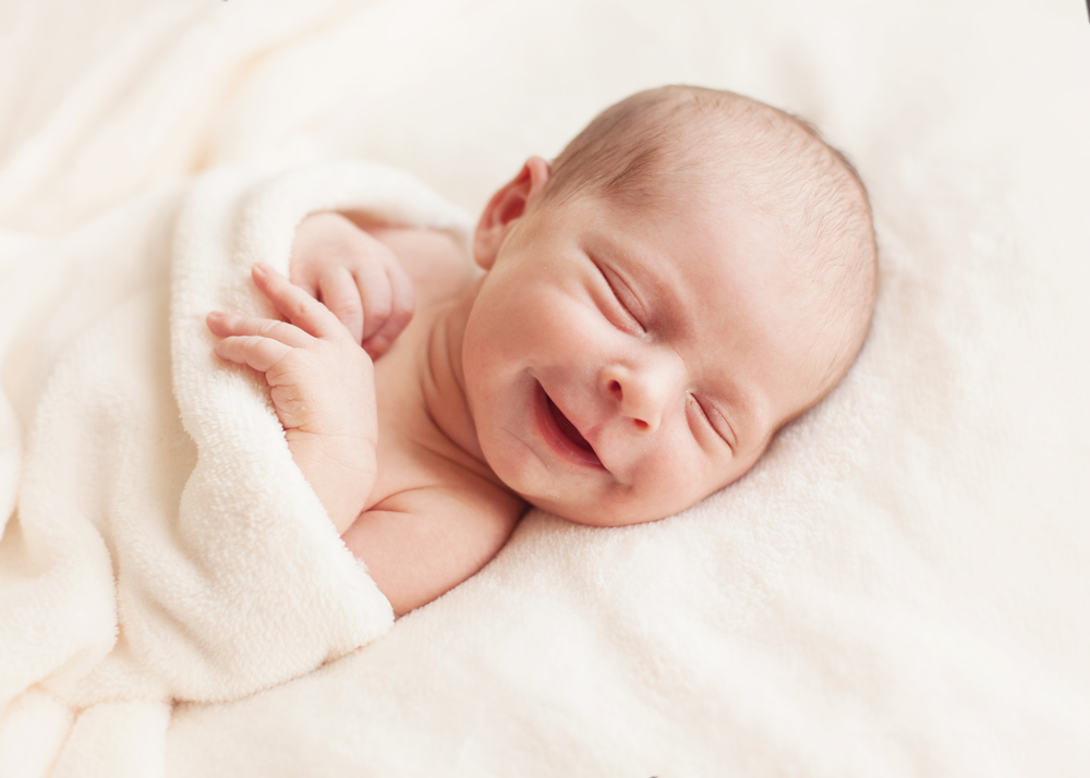 Why Do Babies Smile in Their Sleep? A newborn baby smiles while sleeping